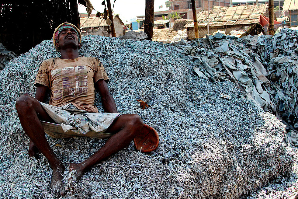 A photo of a worker resting on a mountain of leathers.