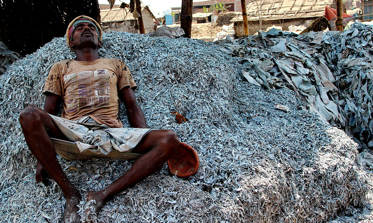 A photo of a worker resting on a mountain of leathers.