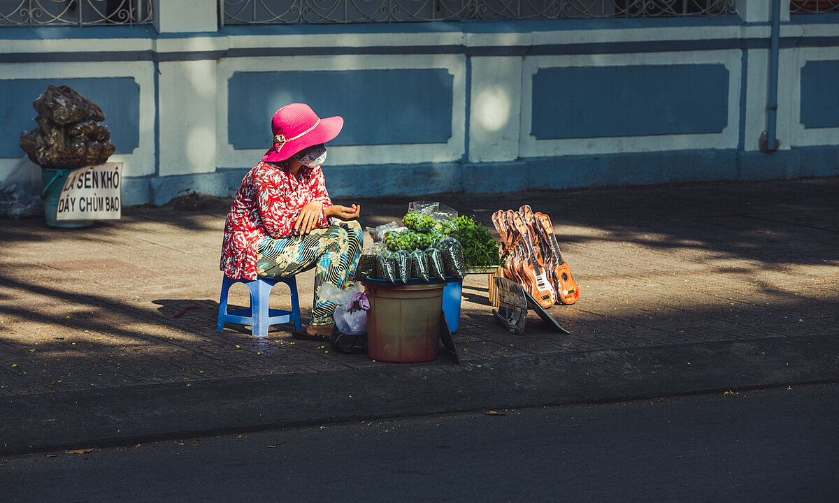 A woman selling fruits, vegetables and toys on a sidewalk of a street in Ho Chi Minh City, Vietnam.