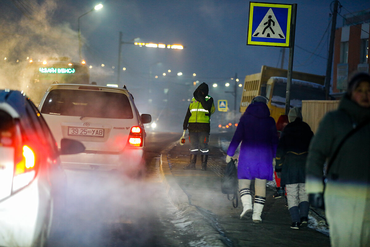 Pedestrians and cars commuting on a road covering with ice