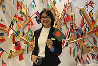 A photo of a woman holding small flags and the background is full of country flags.