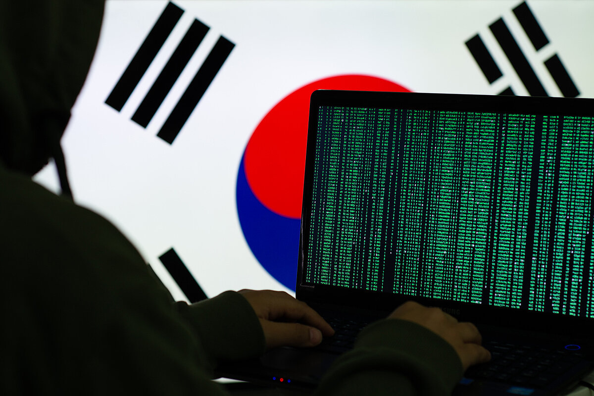 a photo of someone behind a computer typing and a korea flag as background