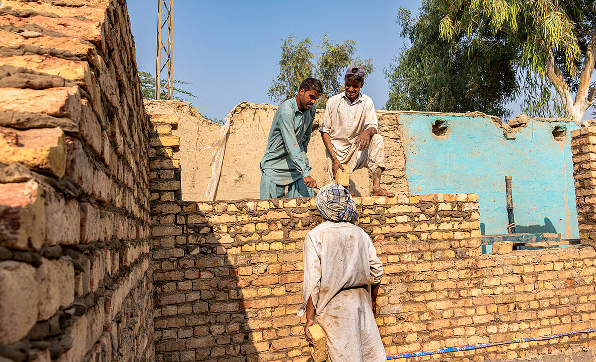 3 male workers piling up bricks