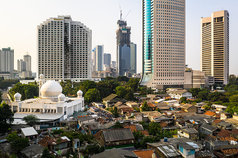 Contrast in Jakarta downtown district with modern skyscrapers, a large mosque and a very crowded low income residential district in Indonesia capital city