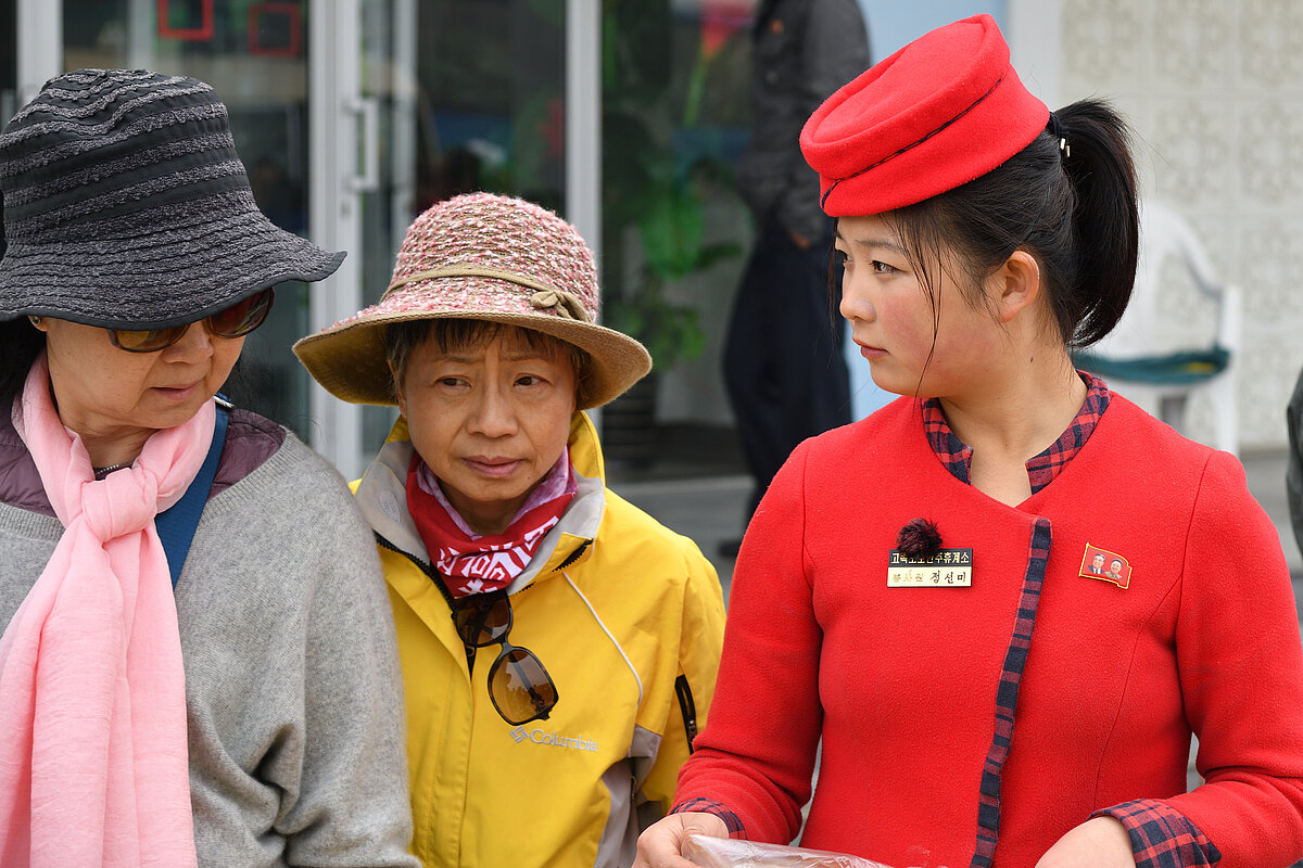 Pyongyang, North Korea - The girl, the seller of a food in uniform and senior chinese tourists.