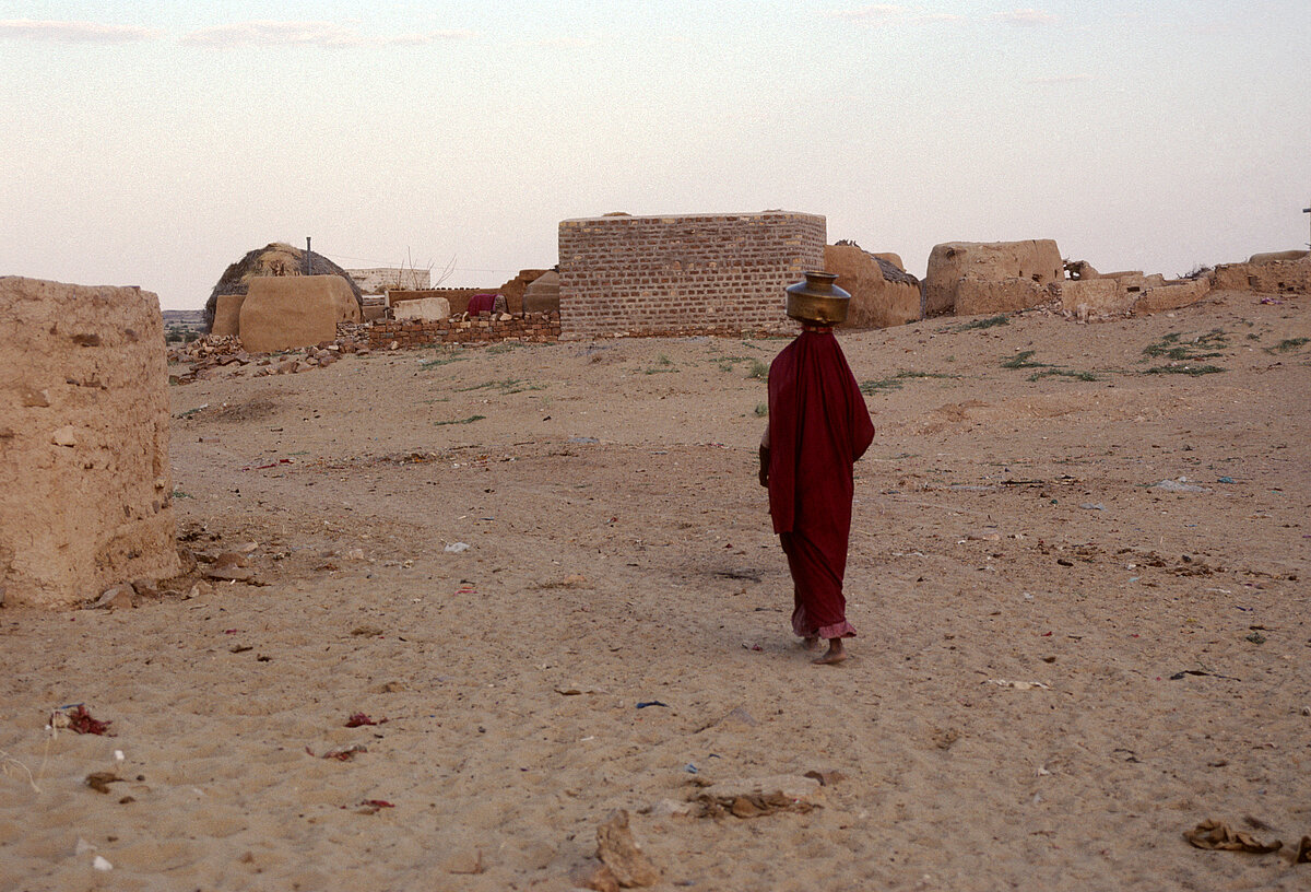 Tribal woman with pot on head in desert