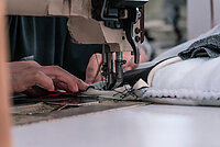 Hands working with seamstress sews on an old sewing machine, threads the fabric.