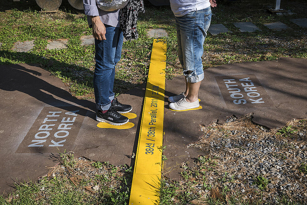 Two tourists visiting the South Korean side of the DMZ stand on a symbolic map of North and South Korea, divided at the 38th Parallel. 