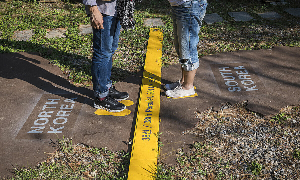 Two tourists visiting the South Korean side of the DMZ stand on a symbolic map of North and South Korea, divided at the 38th Parallel. 