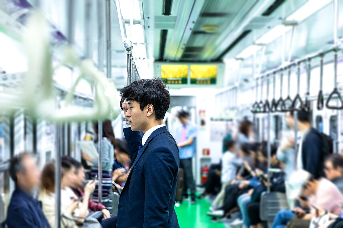 A korean man standing holding an upper rail in a subway train