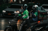 Delivery driver in green uniform riding a motorbike on a street