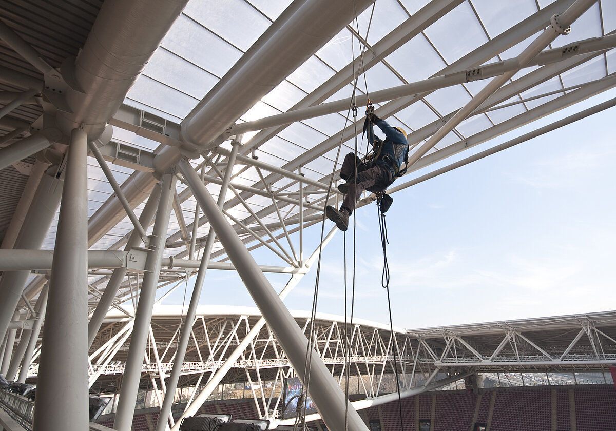 A worker climbing up the construction of stadium roof