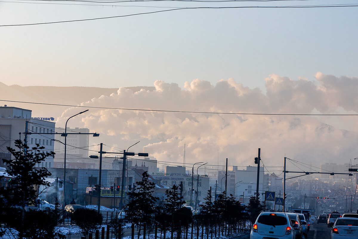 A street in a city with a lot of cars and smoke covering the city