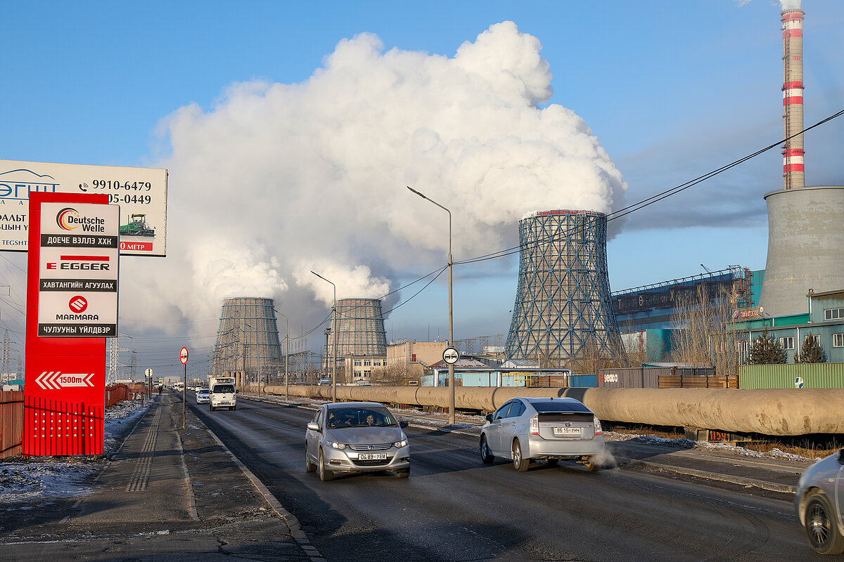 3 large chimneys in a factory releasing heavy smoke in the city