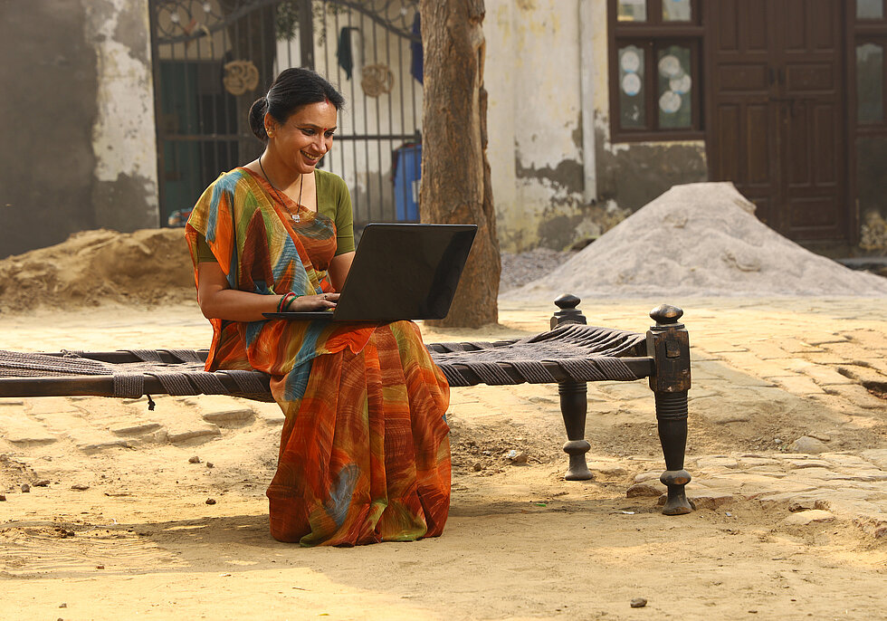 Happy rural Indian women working on laptop in village. She is working with confidence.