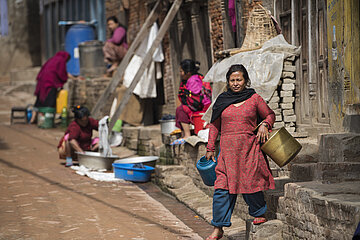 Women wash clothes and dishes on the streets of Patan Durbar Square in Kathmandu, Nepal.