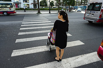Mother with a baby stroller crossing the street in Minh Khai, Hanoi, Vietnam.