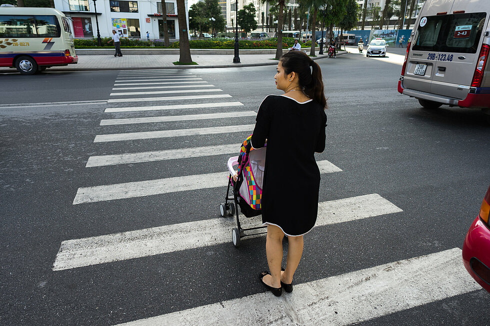 Mother with a baby stroller crossing the street in Minh Khai, Hanoi, Vietnam.