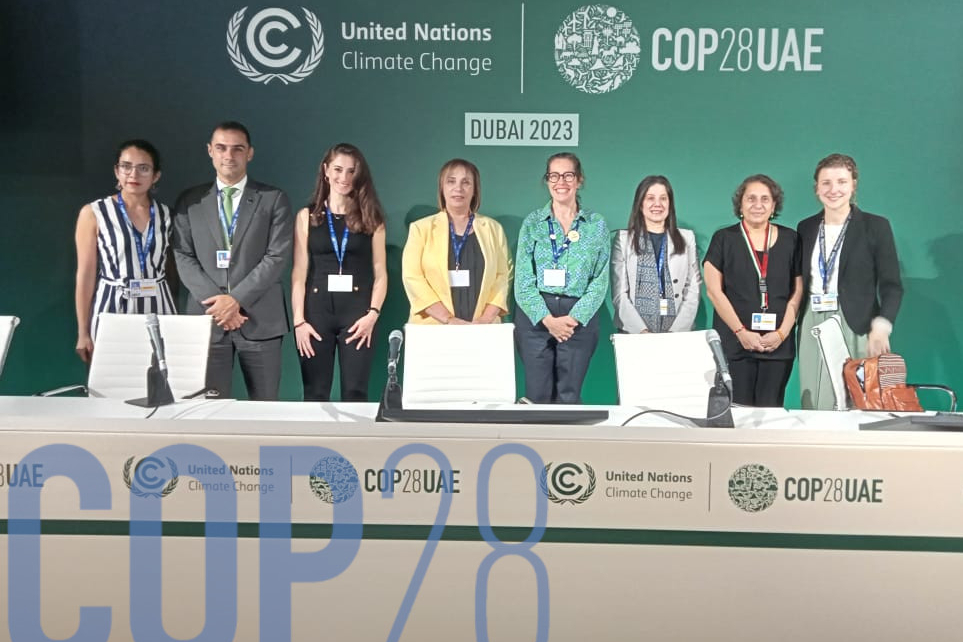 A panel of 8 speakers with a backdrop of COP28